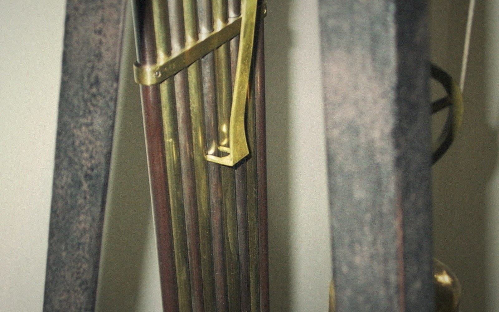 A gridiron pendulum of parallel brass and steel rods hanging in a longcase clock, seen straight on, dim interior